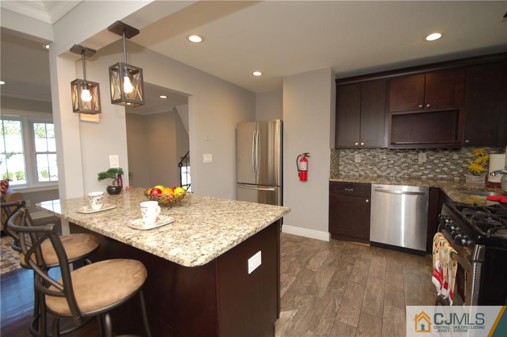 8 Estok Road Edison, NJ 08817 - Photo 14 of 22 a kitchen with stainless steel appliances granite countertop a sink a stove a microwave a dining table and chairs