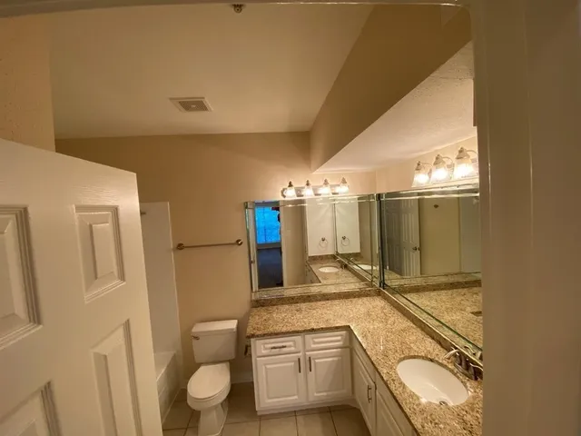 a bathroom with a granite countertop double vanity sink a mirror and a shower