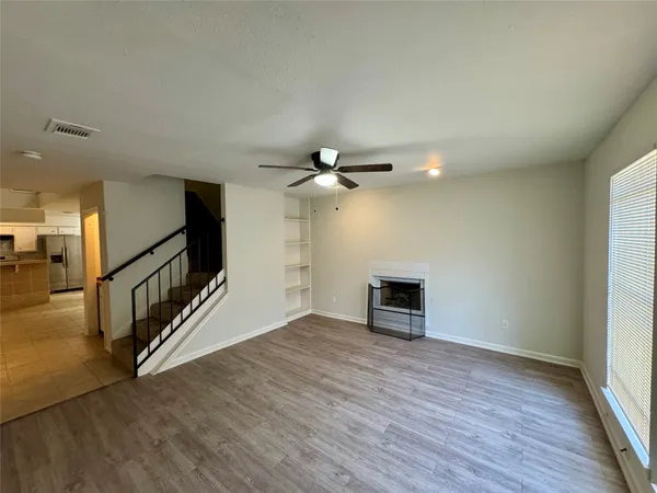 an empty room with wooden floor fireplace and windows