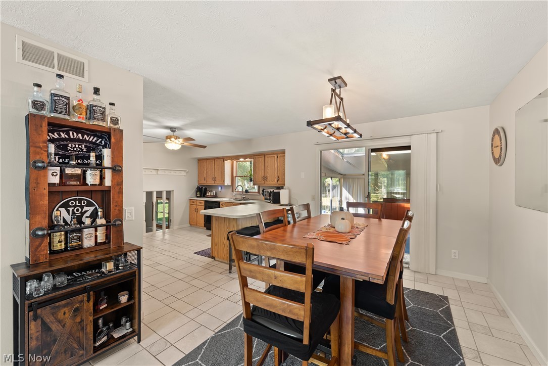 75 Houghton Road Northfield, OH 44067 - Photo 14 of 48 Kitchen and dining area featuring tile flooring, light wood cabinetry, a center island with counter seating, and sliding glass doors