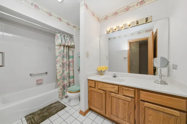a spacious bathroom with a granite countertop sink a toilet a mirror a bathtub and shower