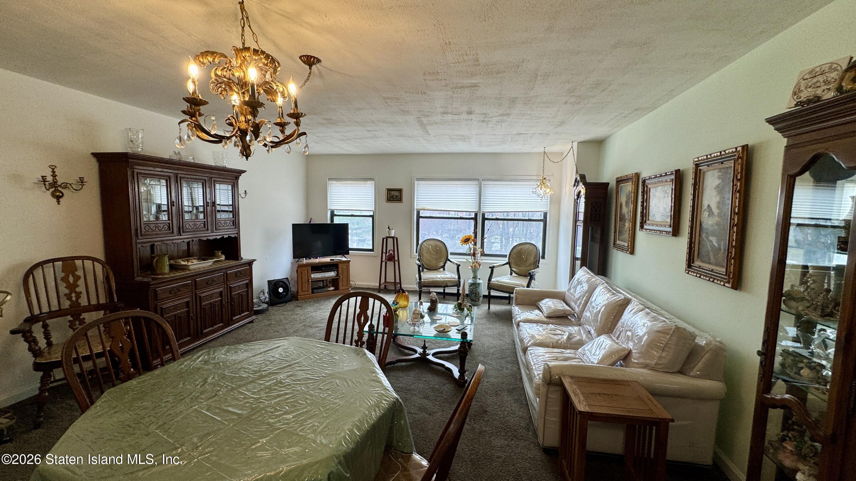 1100 Clove Road, Unit 2B Staten Island, NY 10301 - Photo 18 of 52 a view of a dining room with furniture a chandelier and flat screen tv
