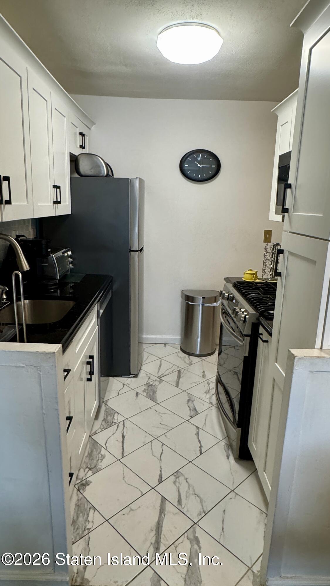 1100 Clove Road, Unit 2B Staten Island, NY 10301 - Photo 25 of 52 a kitchen with granite countertop a refrigerator and a stove