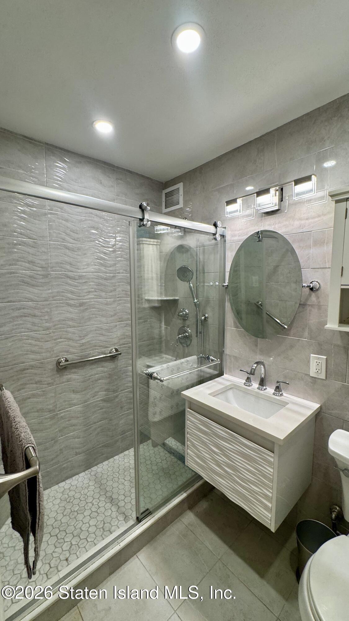 1100 Clove Road, Unit 2B Staten Island, NY 10301 - Photo 26 of 52 a bathroom with a sink mirror and shower