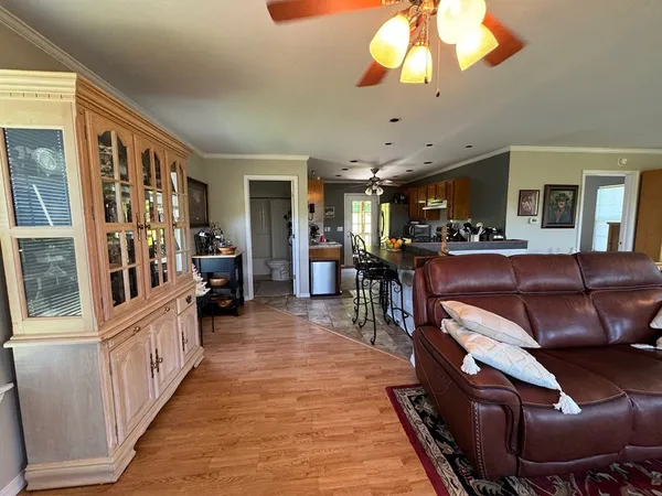 a living room with stainless steel appliances granite countertop furniture wooden floor and a chandelier