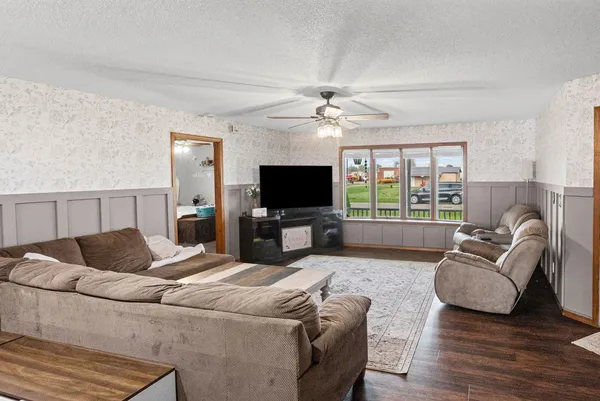 a living room with furniture a flat screen tv and a large window
