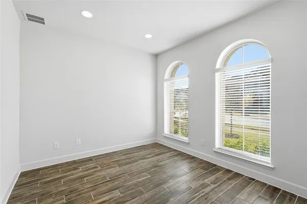 an empty room with wooden floor and windows
