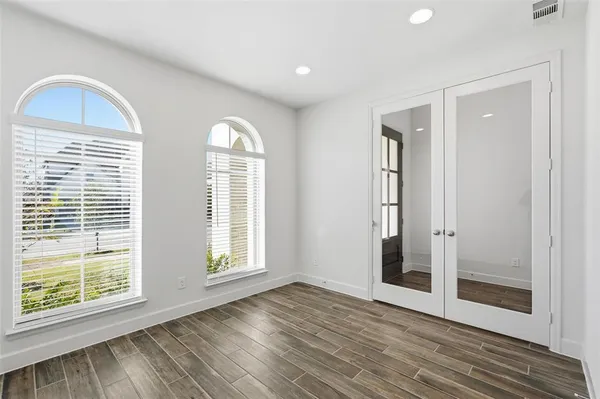 a view of empty room with wooden floor and fan