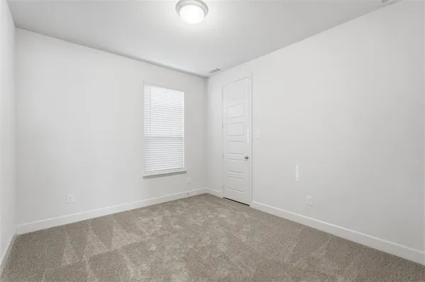an empty room with chandelier fan and windows