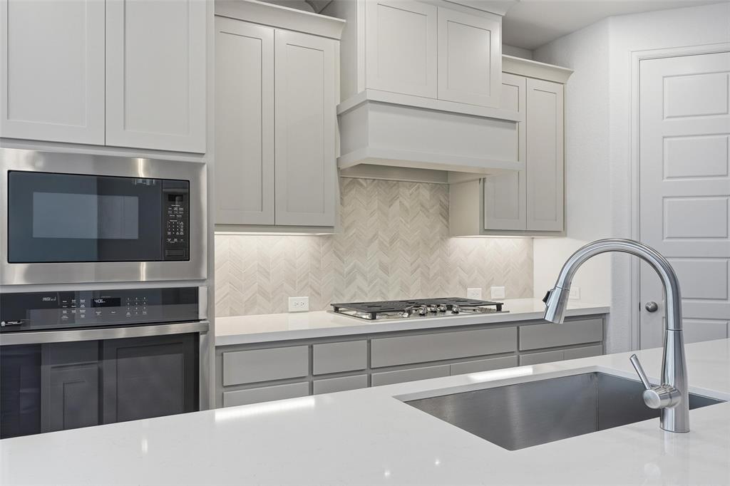 3329 Lacebark Lane Celina, TX 75009 - Photo 6 of 35 a kitchen with stainless steel appliances kitchen island a stove and a microwave