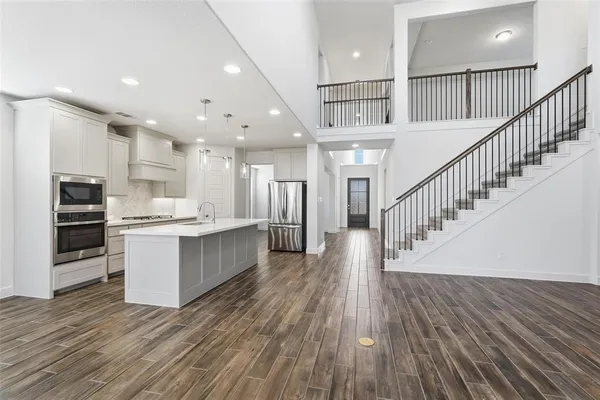 a view of kitchen with kitchen island wooden floor center island and stainless steel appliances
