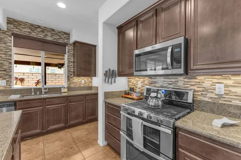 a kitchen with stainless steel appliances a refrigerator a stove a sink and a dining table