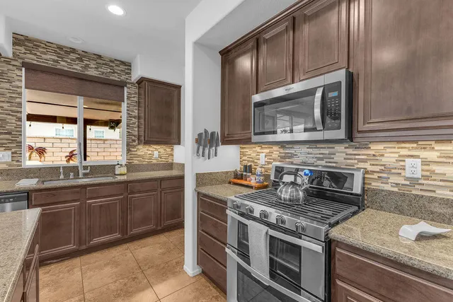 a kitchen with stainless steel appliances a refrigerator a stove a sink and a dining table