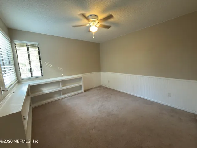 an empty room with a window and a ceiling fan