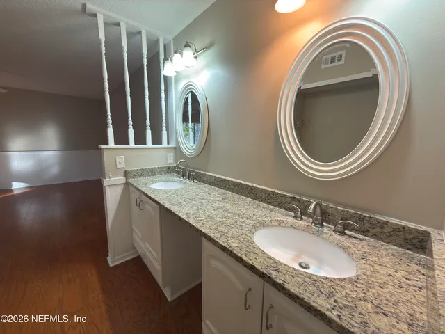 a bathroom with a granite countertop double vanity sink and a mirror
