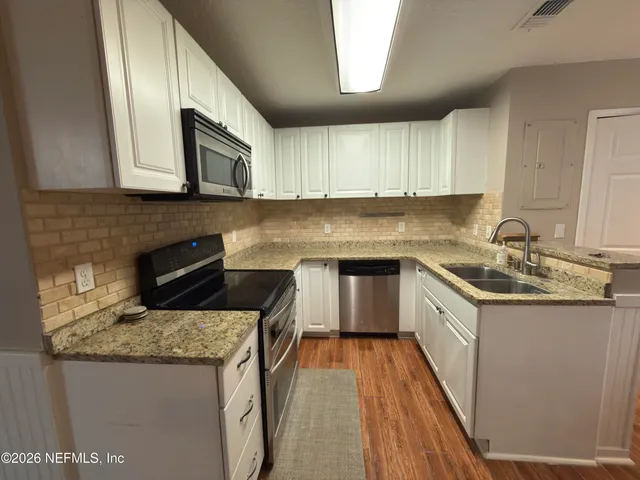 a kitchen with granite countertop a sink a stove and cabinets