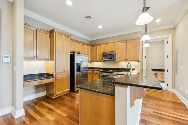 a kitchen with stainless steel appliances granite countertop a refrigerator a stove and a sink