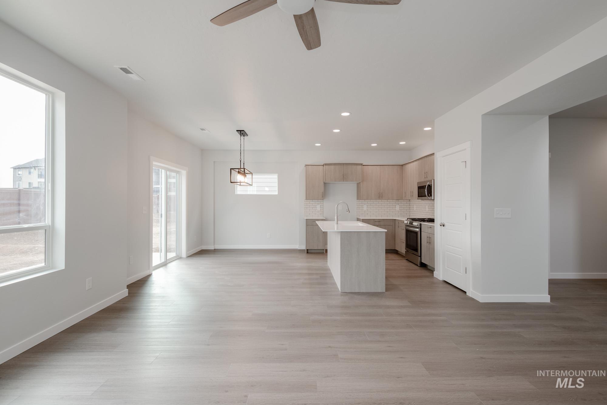 910 North Mirror Creek Way Meridian, ID 83642 - Photo 26 of 27 Kitchen featuring open floor plan, light wood-style flooring, backsplash, light brown cabinets, and an island with sink