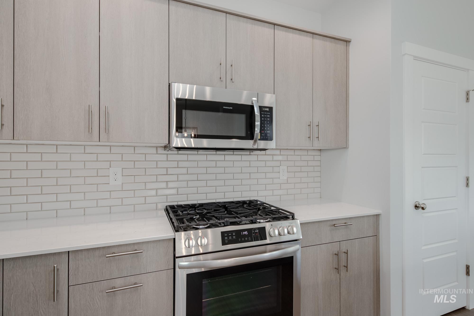 910 North Mirror Creek Way Meridian, ID 83642 - Photo 8 of 27 Kitchen featuring appliances with stainless steel finishes, light brown cabinetry, backsplash, light stone countertops, and modern cabinets