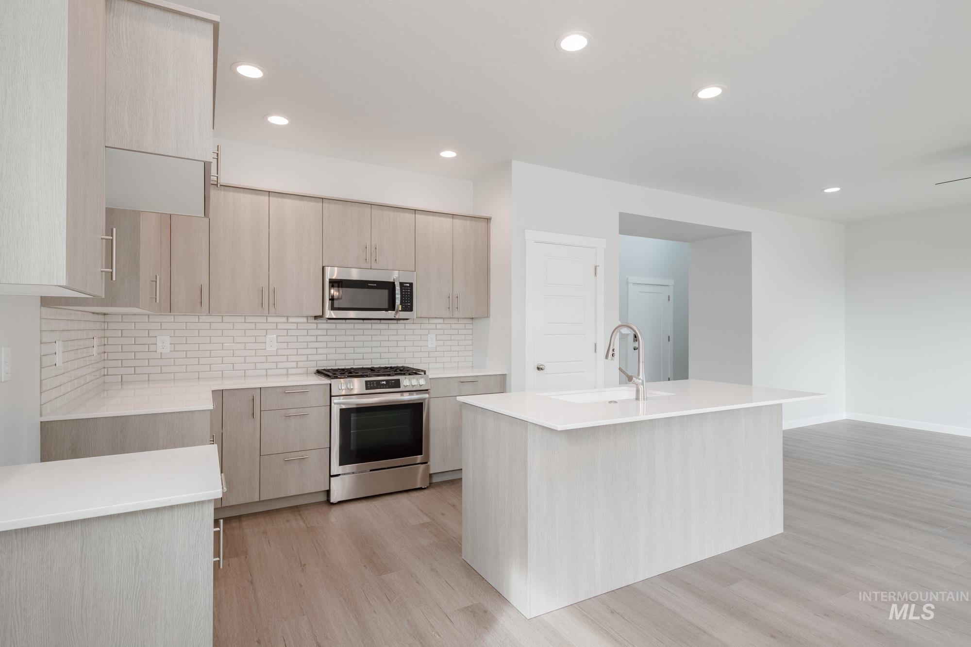 910 North Mirror Creek Way Meridian, ID 83642 - Photo 9 of 27 Kitchen featuring stainless steel appliances, light stone counters, light brown cabinetry, modern cabinets, and recessed lighting