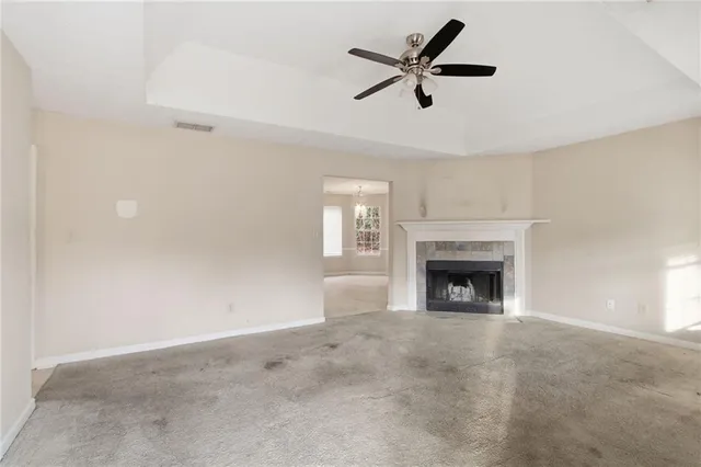 a view of a livingroom with a fireplace a ceiling fan and a window