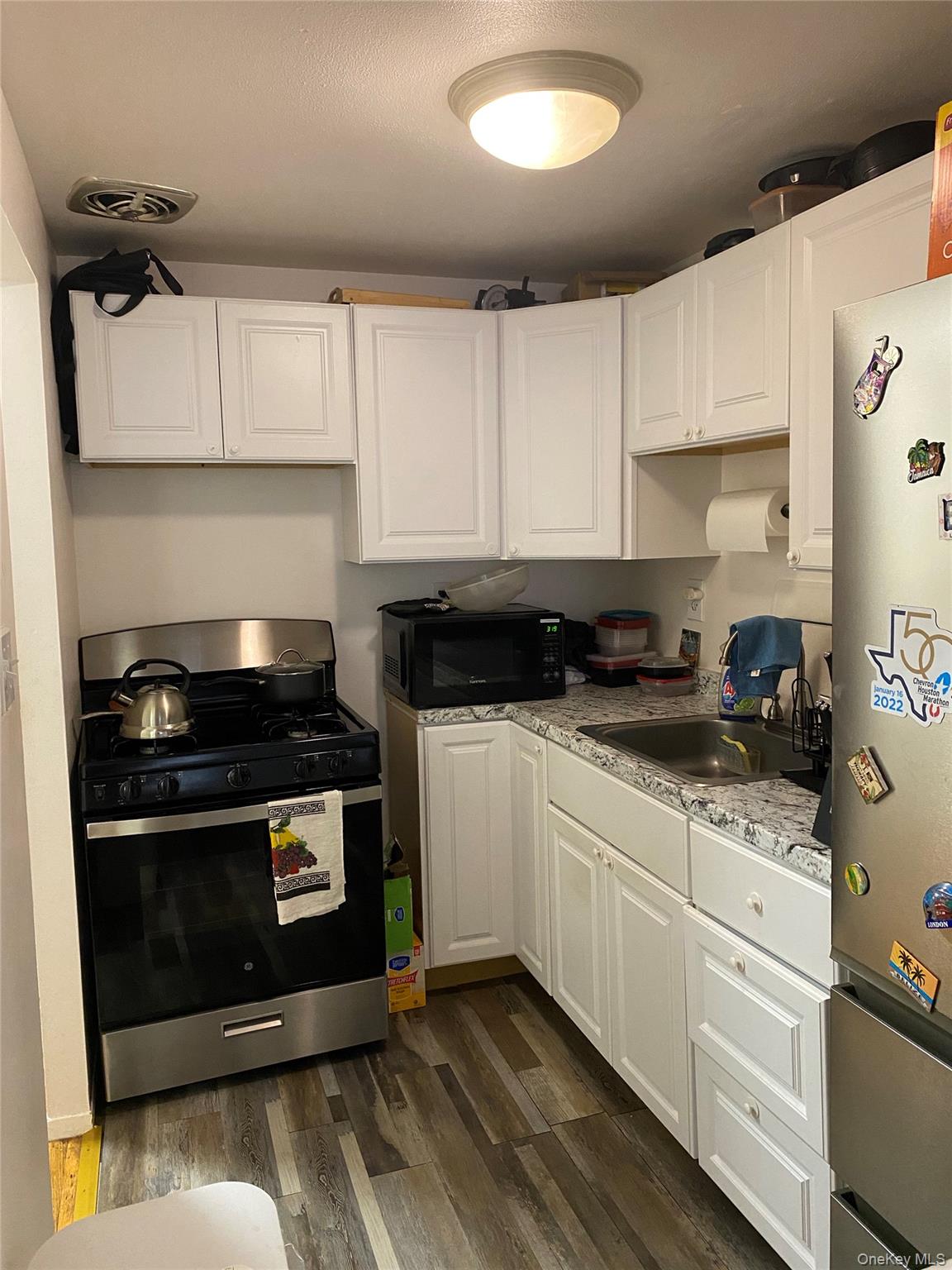 84-24 98th Street, Unit 1 Queens, NY 11421 - Photo 4 of 22 a kitchen with stainless steel appliances granite countertop a stove and white cabinets