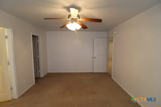 an empty room with a chandelier fan and closet