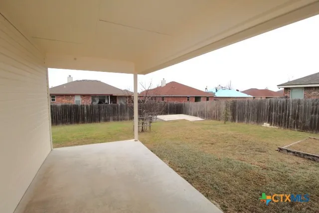 a view of a backyard with table and chairs under an umbrella