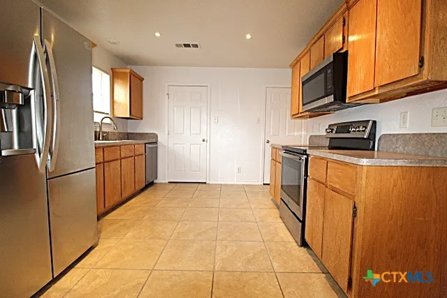 a kitchen with stainless steel appliances granite countertop a refrigerator stove top oven and sink