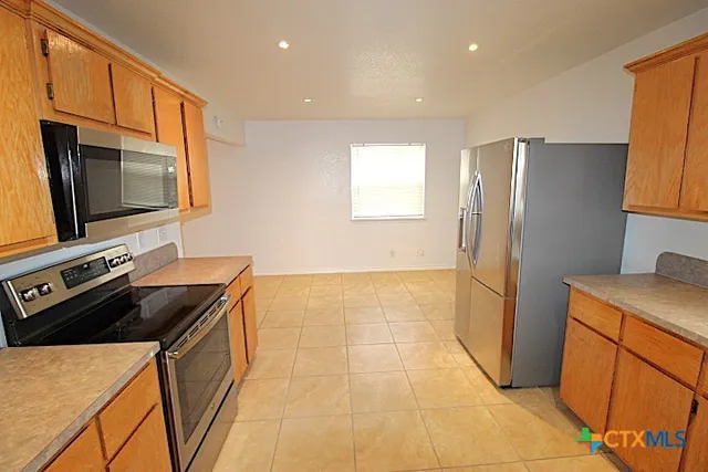 a kitchen with stainless steel appliances a stove a refrigerator a sink a counter top space and cabinets