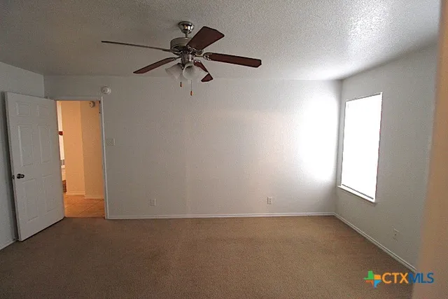 an empty room with windows and fan