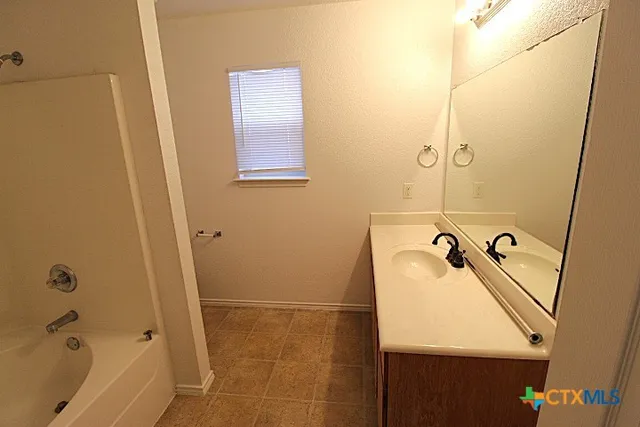 a bathroom with a tub sink and mirror