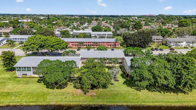 a patio with a table and chairs under an umbrella with palm trees