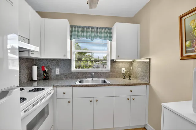 a kitchen with white cabinets and window