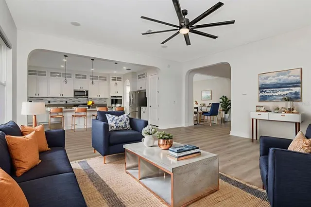 a large kitchen with stainless steel appliances granite countertop a refrigerator a oven a white stove a sink and white cabinets with wooden floor