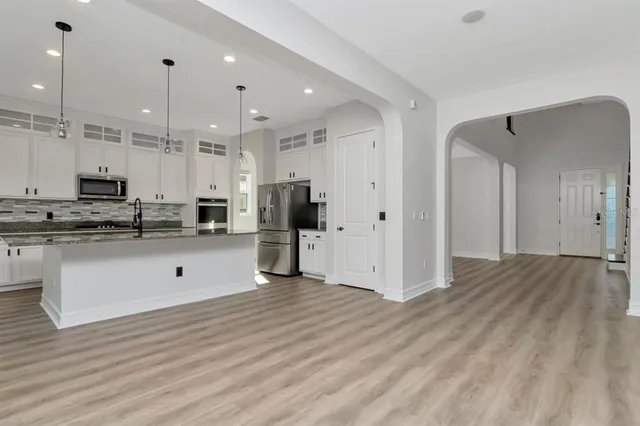 a large kitchen with stainless steel appliances granite countertop a sink stove and cabinets