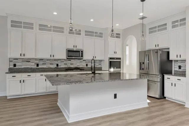 a kitchen with stainless steel appliances granite countertop a sink a oven a refrigerator and a counter top space
