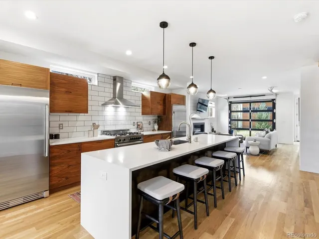 a kitchen with stainless steel appliances kitchen island granite countertop a table chairs in it and wooden floors
