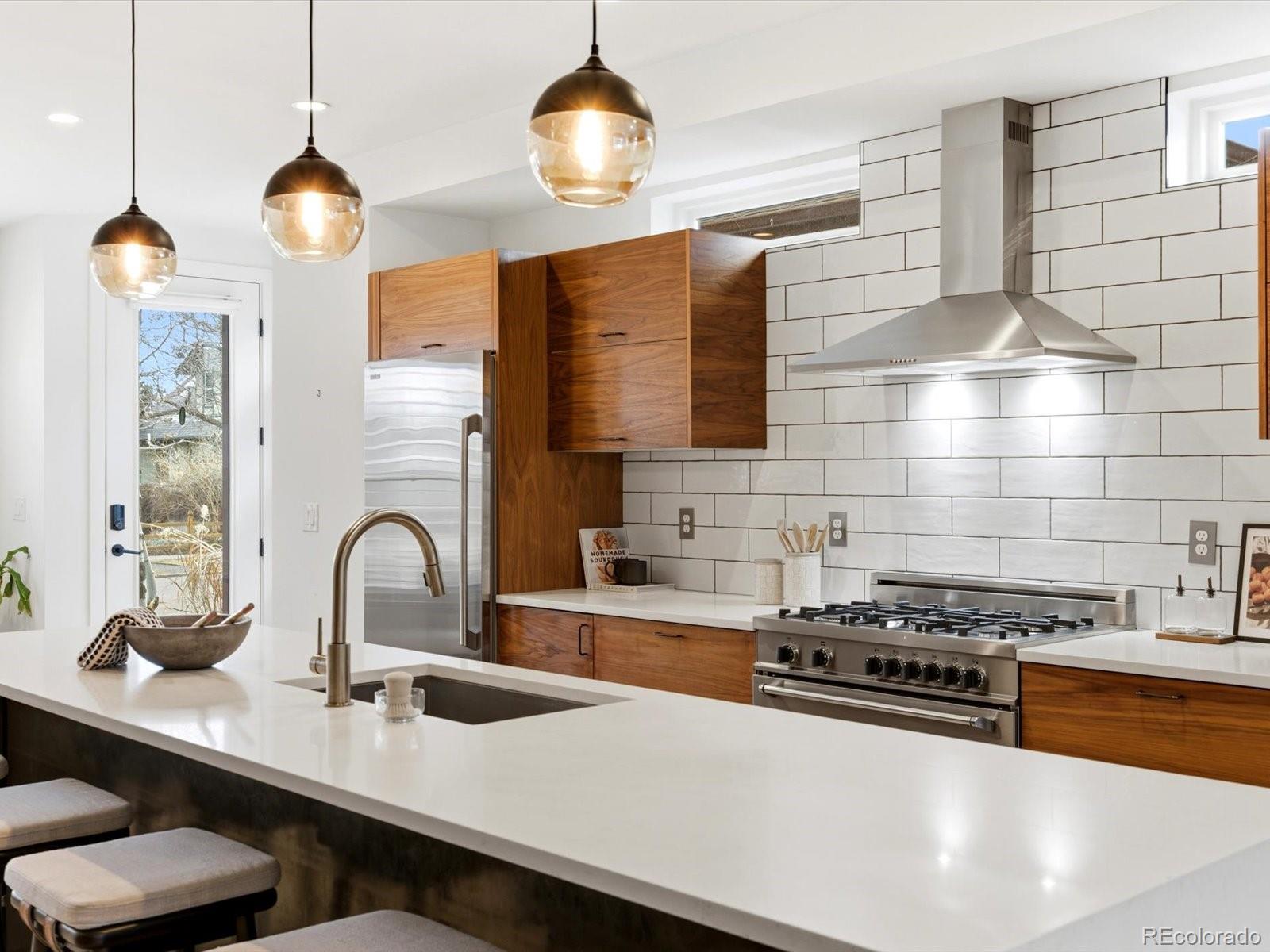 4141 Shoshone Street Denver, CO 80211 - Photo 9 of 50 a kitchen with stainless steel appliances a sink a stove and a wooden floor