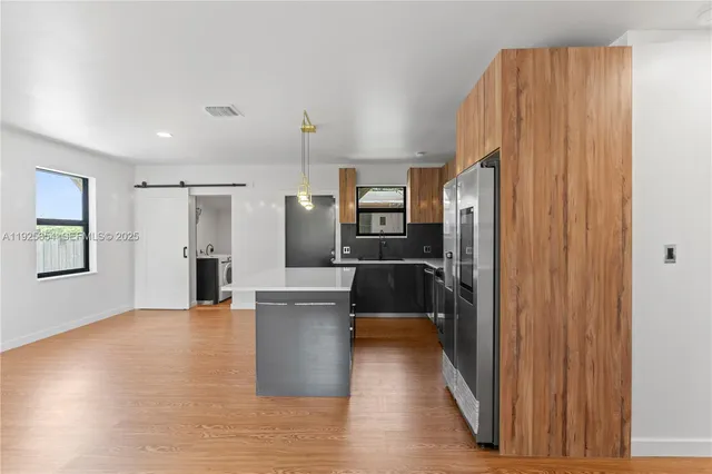 a kitchen with stainless steel appliances a refrigerator and wooden floor