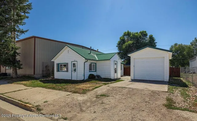 a view of a house with a yard and large tree