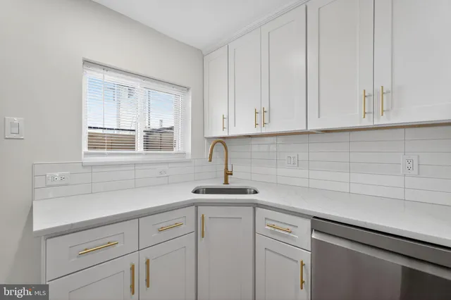 a kitchen with white cabinets and a window