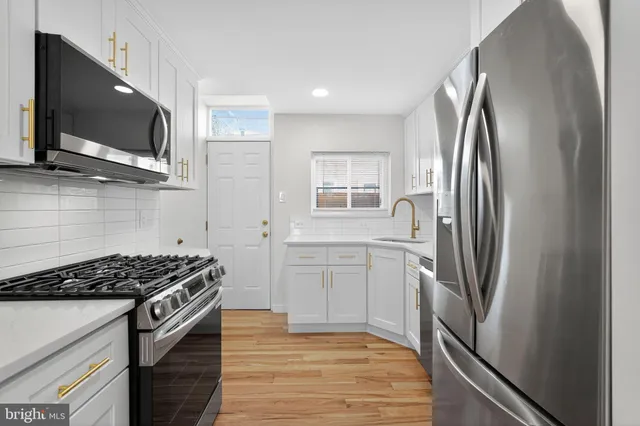 a kitchen with stainless steel appliances granite countertop a refrigerator stove top oven and sink