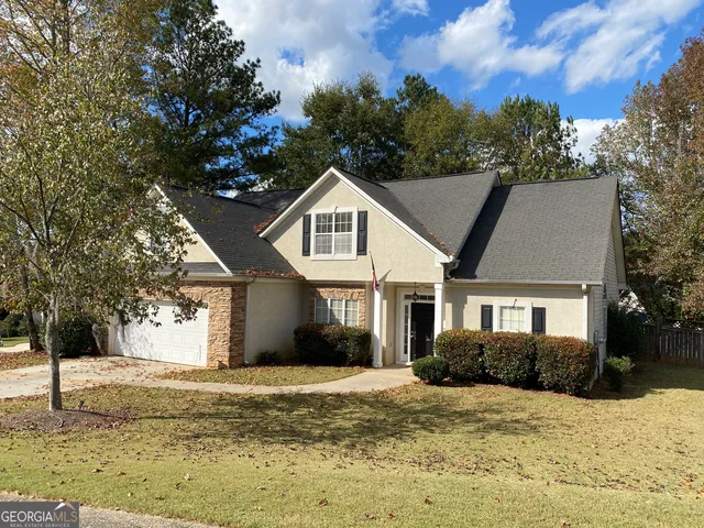 a front view of a house with a yard covered with trees