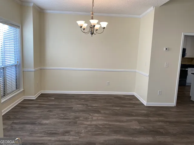 an empty room with wooden floor and chandelier