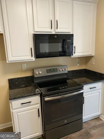 a kitchen with granite countertop white cabinets and stainless steel appliances