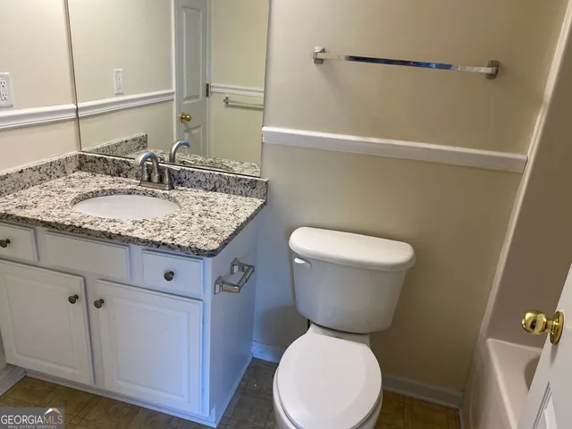 a bathroom with a granite countertop toilet sink and mirror