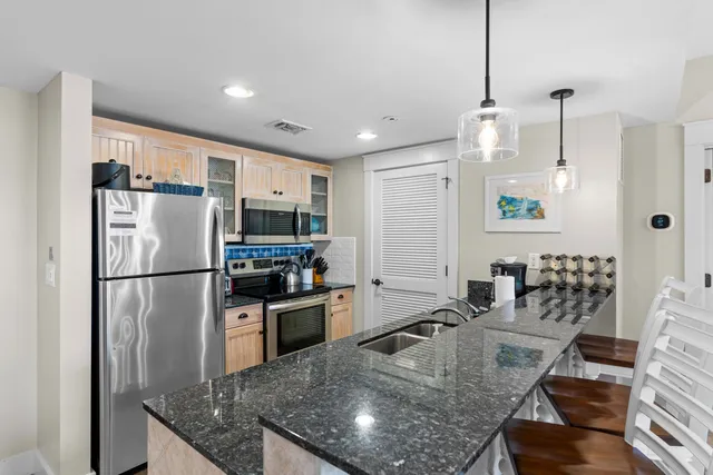 a kitchen with stainless steel appliances granite countertop a refrigerator a stove a sink a dining table and chairs