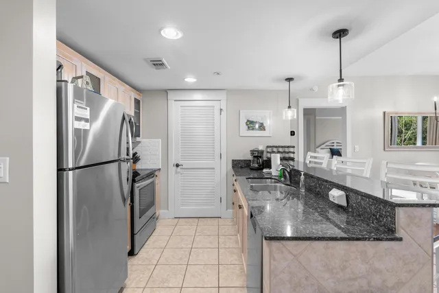 a kitchen with stainless steel appliances granite countertop a refrigerator a sink and white cabinets