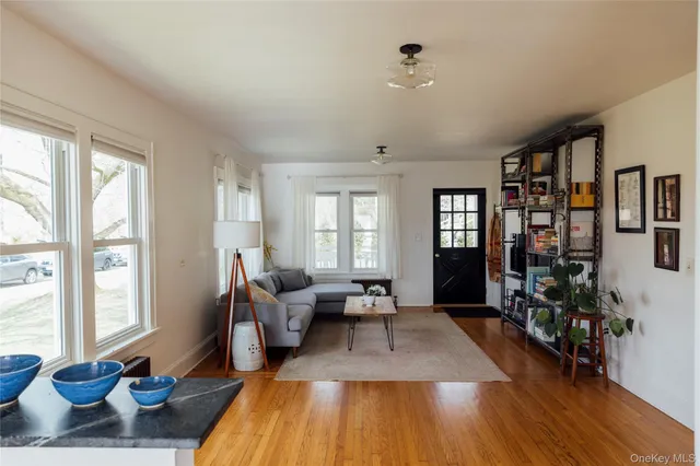 a living room with furniture large window and wooden floor
